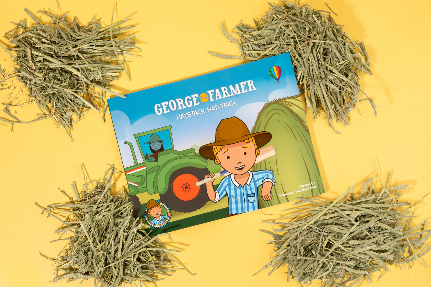 A picture book titled 'George the Farmer' with a illustration of a man in a hat standing next to a green tractor, placed on a background featuring haystacks.